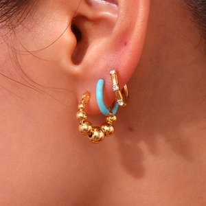Macro shot of 18K gold plated hoop earrings set with gradient beads and blue enamel