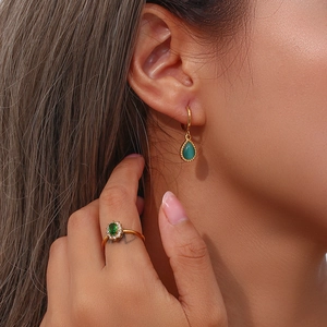 Detalle de pendientes y anillo chapados en oro con piedras de opale verde elegante