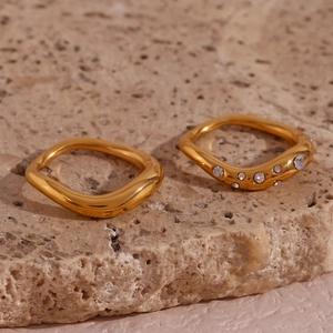 Detailed view of 18K gold plated wavy rings with crystal inlay on stone surface