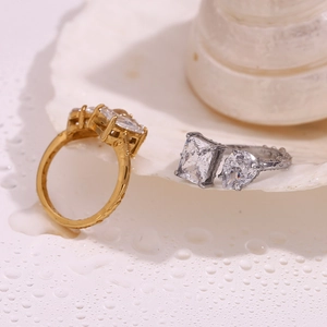 Detail view of 18K gold and silver rings with zircon stones on shell background