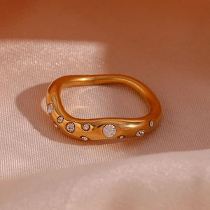 Detailed view of wave-shaped 18K gold-plated ring with micro-set zircon on silk