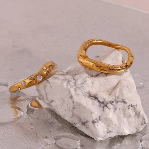 Macro view of gold plated 18K stainless steel wavy rings with crystal pavé on marble