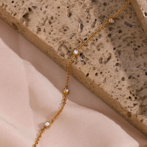 Detail van gouden ketting met verfijnde zirkonia op zachte roze zijden stof