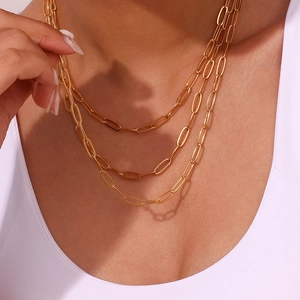 Detail van een drielaagse 18K vergulde paperclip-schakelketting op de hals van een model