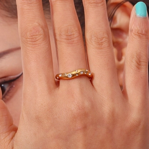 Detail shot of 18K gold plated wavy ring with micro-inset zircons on a model's finger