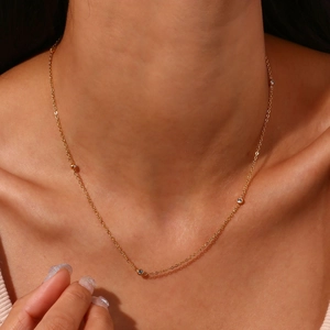 Detailopname van een gouden ketting met fonkelende zirkoonkralen bij een vrouwelijk model