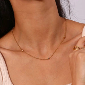 Fijne gouden ketting met gepolijste kralen en fonkelende zirkoon op de hals van model