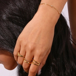 Detail van gouden stapelbare ringen en een verfijnde armband met zirkoniasteentjes