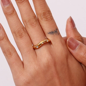 Macro detail of wave-shaped 18K gold-plated ring with micro-pave cubic zirconia on hand