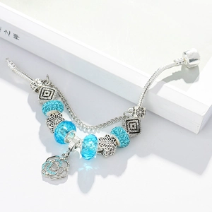 Silver snake chain bracelet with sparkling blue charms and rose pendant on white background