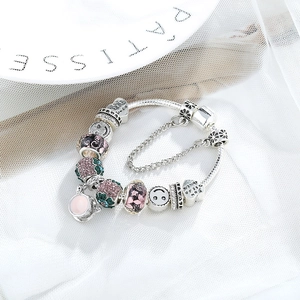 Bracciale a sfere d'argento con ciondoli a calice e cuore su un piatto di porcellana