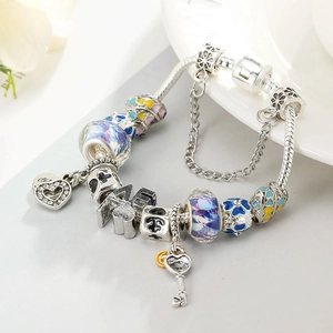 Détail de breloques cœur et clé sur un bracelet en argent avec perles de verre violettes