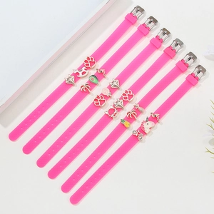 Pink silicone charm bracelet set with unicorn and flamingo enamel beads on white surface
