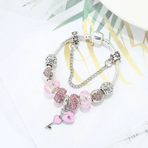 Charmantes silbernes Perlenarmband mit rosa Kristallherz und Schlüsselanhängern auf Weiß