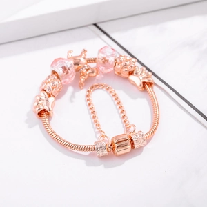 Bracelet à breloques élan en or rose avec perles en verre rose sur fond marbre