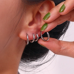 Detail of silver stainless steel hoop earrings worn on various ear piercing positions