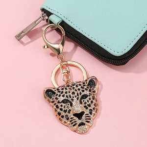 Dettaglio portachiavi a forma di leopardo con cristalli appeso a un portafoglio verde
