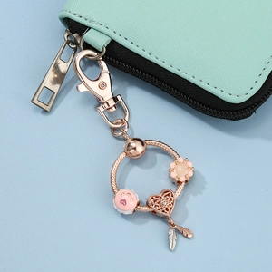 Rose gold mom charm keychain with dreamcatcher and beads attached to a mint leather bag