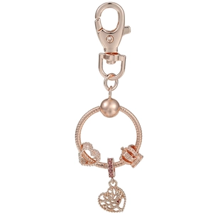 Détail d'un porte-clés or rose avec pendentif cœur arbre de vie et breloque couronne