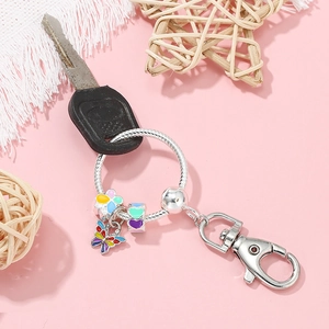 DIY sleutelhanger met kleurrijke vlinder en hartbedeltjes aan een zilveren ring