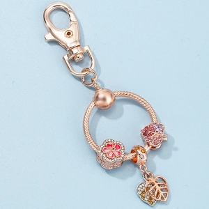 Rose gold keychain with diamond-studded leaf, flower charms, and a heart pendant