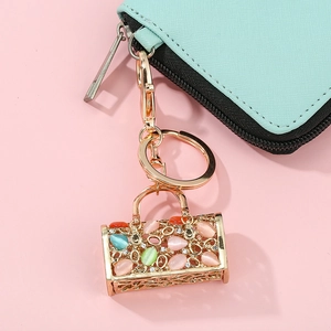 Porte-clés sac à main chic avec strass colorés sur un portefeuille menthe et fond rose