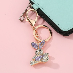 Close-up of golden bunny keychain with purple rhinestones on a mint green wallet