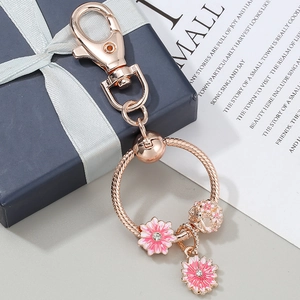 Rose gold daisy keychain with pink enamel charms and lobster clasp on a gift box