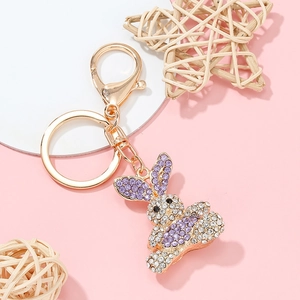 Macro detail of golden bunny keychain with purple rhinestones on a decorative pink display