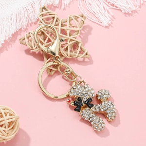 Close-up of golden poodle keychain with sparkling rhinestones and a black bow detail