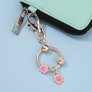 Rose gold daisy flower keychain with pink enamel charms and lobster clasp on light blue base