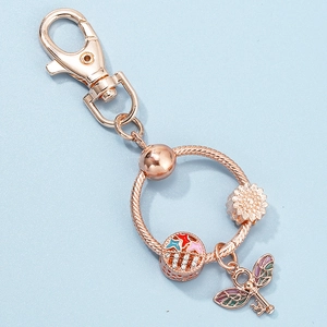 Rose gold DIY keychain with sunflower pendant and winged key charm on blue background
