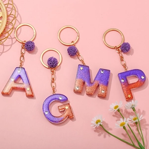 Glittery purple resin alphabet keychain set with gold stars and purple pom pom charms
