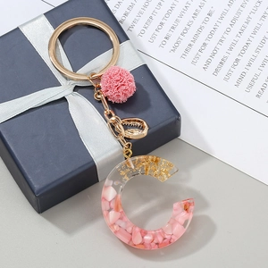Dettaglio del portachiavi con lettera C in resina con pietre rosa e foglia d'oro