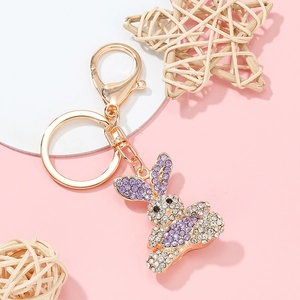 Golden rabbit keychain with purple rhinestones on a pink minimalist background