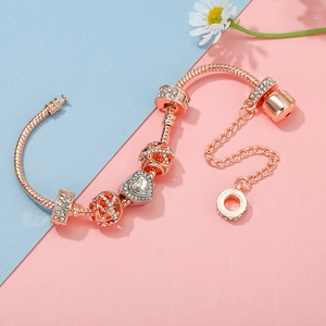 Rose gold crown bracelet with pink heart pendant and sparkling charms on a blue background