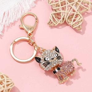 Détail d'un porte-clés chat doré orné de strass roses et blancs sur fond rose