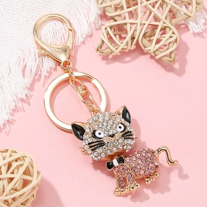 Détail du porte-clés chat doré avec cristaux roses sur un décor rose élégant