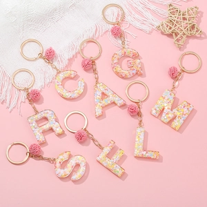 Vue détaillée des porte-clés alphabet en résine avec paillettes cœur et pompon rose