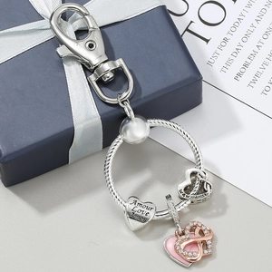 Silver heart keychain with Love engraving and infinity symbol on a navy gift box