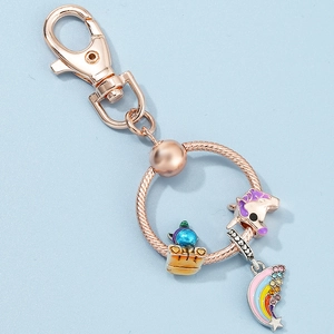 Rose gold cartoon keychain featuring unicorn, rainbow pendant and blue charm on snake chain