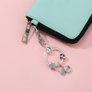 Porte-clés argenté DIY avec breloques étoile, cœur et flocon sur un portefeuille vert