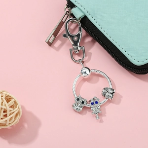 Silver owl beaded keychain charm on light blue cross-grain textured leather wallet