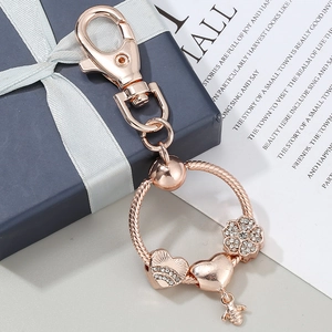 Portachiavi in oro rosa con ciondoli a cuore, fiore e ape su un anello a serpente