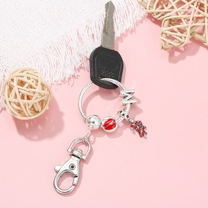 Silver keychain with gingerbread man and red lips charms on a car key background