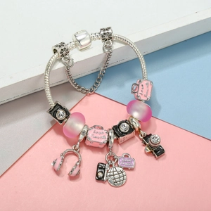 Detail of travel charm bracelet with camera, suitcase pendants and pink beads