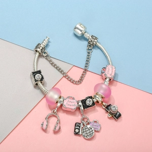 Macro shot of silver-plated travel charms featuring pink luggage and camera detail