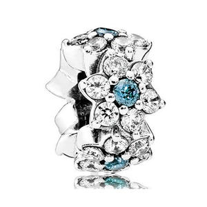 Silver flower charm with blue and white zircons, macro view on white background