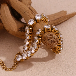 Dettaglio del bracciale tennis placcato oro 18K con zirconi bianchi su legno naturale