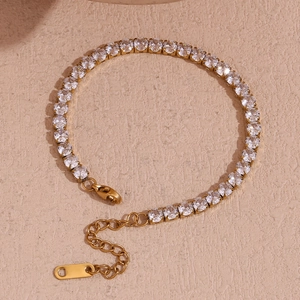 Dettaglio macro del bracciale tennis dorato con zirconi brillanti e chiusura a moschettone